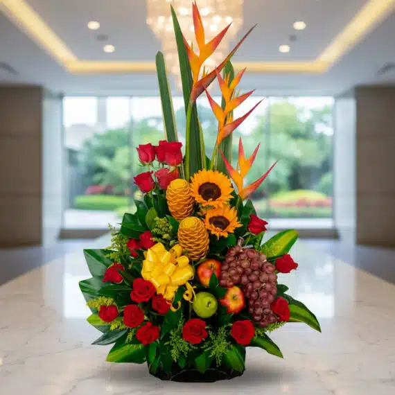 Arreglo Floral con Frutas Durio: Elegancia Tropical para tu Hogar Arreglo floral premium con rosas rojas, girasoles, aves del paraíso, frutas durio, uvas y manzanas, sobre mármol en un lobby