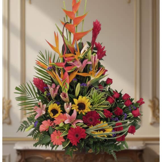 Arreglo floral IDARA con rosas rojas, girasoles, lirios, heliconias y jengibre rojo en un fondo elegante y bien iluminado.