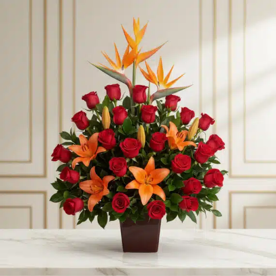 Arreglo Floral Me Encantas: Lirios Naranjas y Rosas Rojas Vibrantes Arreglo floral 'Me Encantas' con lirios naranjas, rosas rojas y aves del paraíso, sobre una mesa de mármol en un entorno eleg