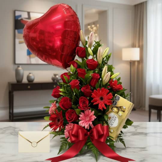 Arreglo floral "Te Amo" con rosas rojas, liliums blancos, gerberas rosadas y rojas, follaje verde, globo de corazón rojo, cho