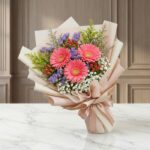 Bouquet Floral LIA con gerberas amarillas vibrantes, envuelto en papel coreano elegante, sobre una superficie de mármol pulid