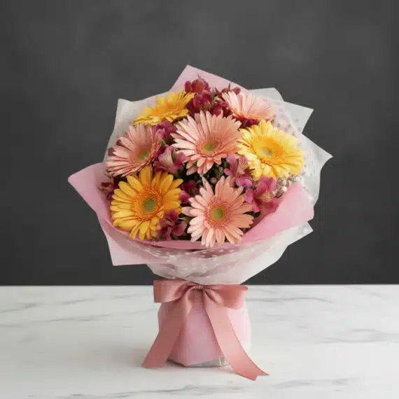 Bouquet de Gerberas Multicolor: Frescura y Elegancia para Regalar Bouquet de gerberas multicolor en tonos pastel (rosas y amarillas) con alstroemerias, envuelto en papel rosa y blanco, sobre
