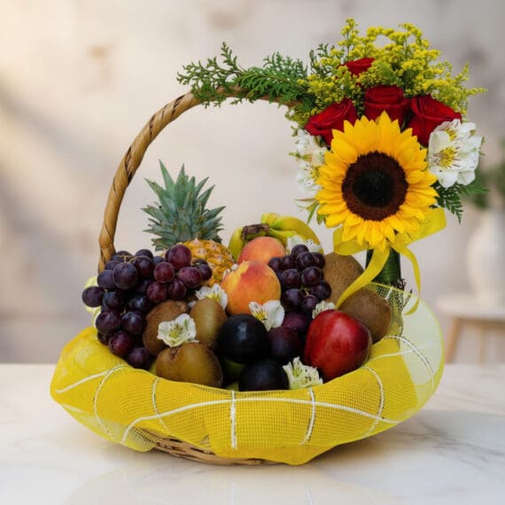Canasta de Frutas Draco con Arreglo Floral Elegante para Regalo Canasta de Frutas Draco con uvas, manzanas, duraznos, kiwis, piña y arreglo floral de rosas, girasol y flores blancas sobre m