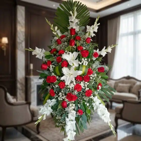 Pedestal Fúnebre Homenaje: Elegancia y Respeto en Rosas y Lirios Pedestal fúnebre Homenaje con rosas rojas, lirios blancos y gladiolos, en una sala de velación premium con luz natural suave.